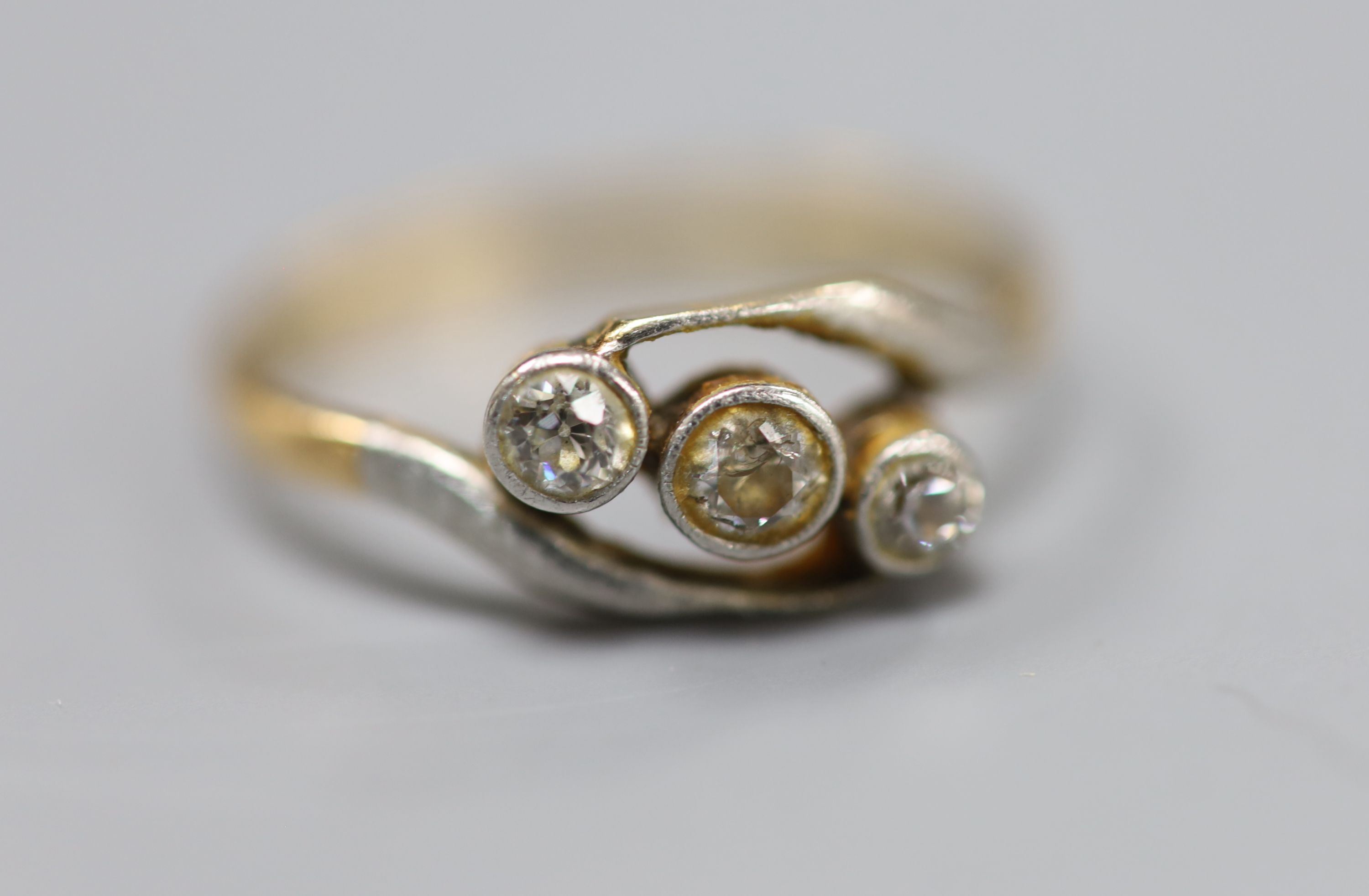 An 18ct and three stone diamond set crossover ring, size Q, gross 2.4 grams.